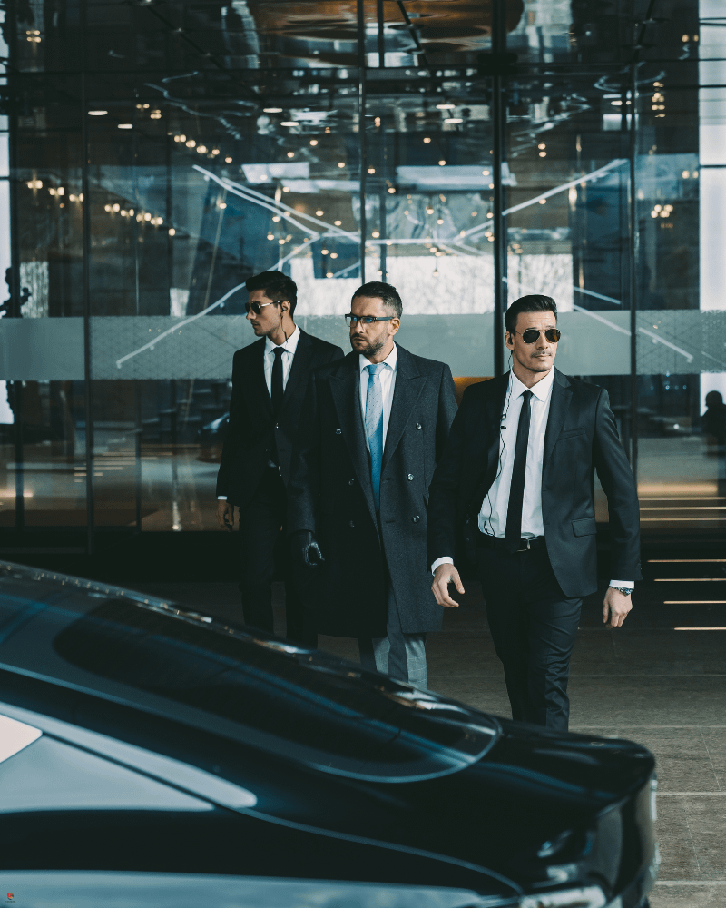 Executive protection services with professional VIP bodyguards escorting a client to secure transport outside a corporate building.